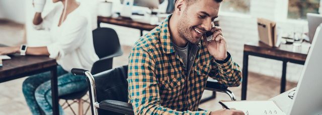 A man in a wheelchair working at his desk.